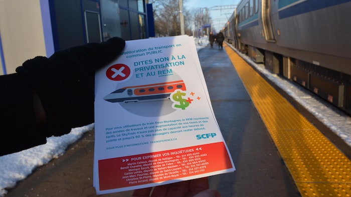 A Hand Holds A Brochure On The Station Platform.