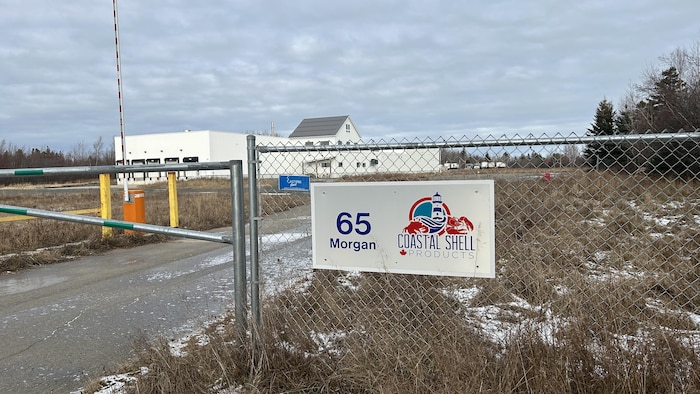 Une enseigne à l'entrée de l'usine avec l'édifice en arrière-plan.