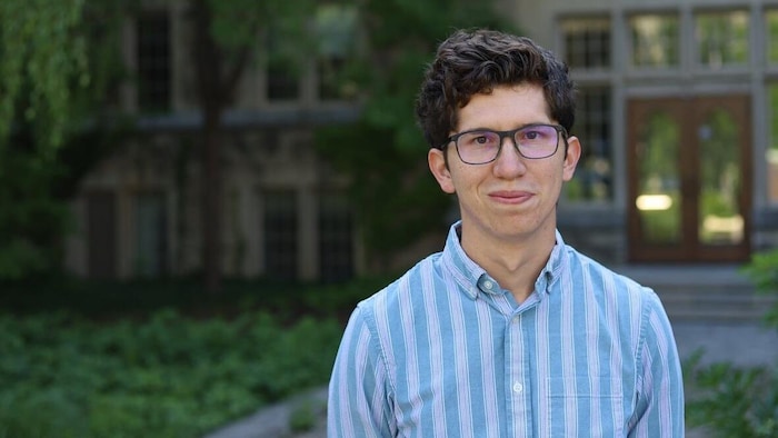 Professor Cody Groat in front of a college building.