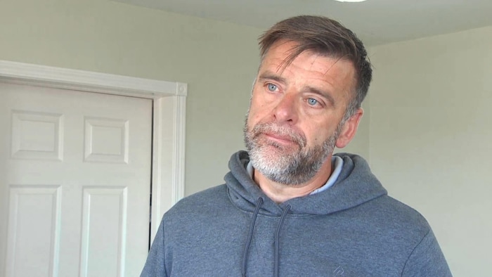 Un homme à l'intérieur incline la tête vers la gauche et semble en intense réflexion.