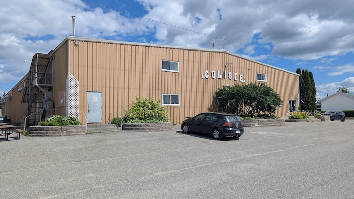 Vue extérieure du Colisée, avec une voiture stationnée devant. 