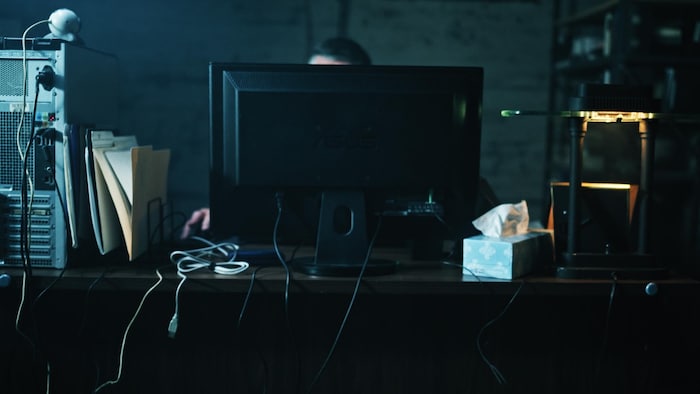 Un homme est caché derrière un écran d'ordinateur à son bureau. 