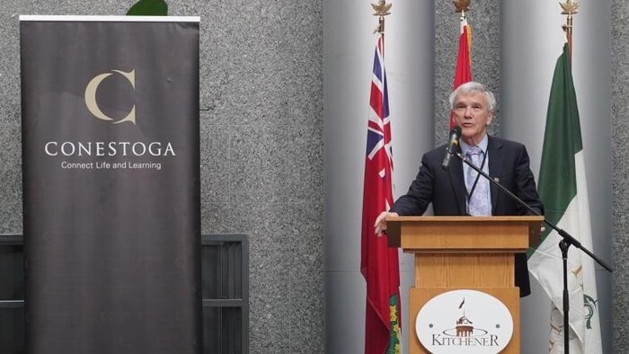 Le président du Collège Conestoga, John Tibbits debout derrière un lutrin. 