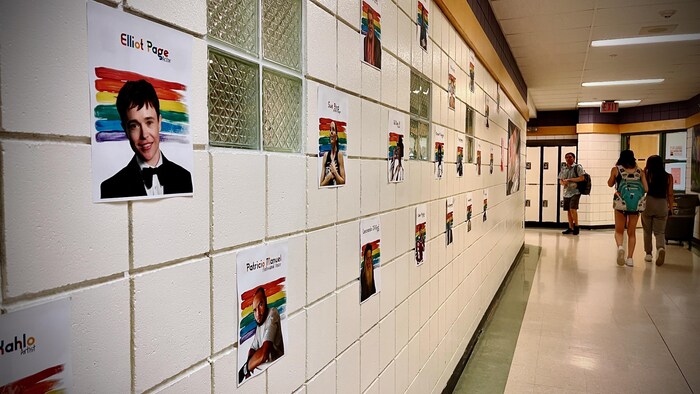 Des posters de vedettes LGBTQ+ sont sur le mur à l'interieur de l'école.