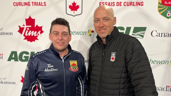 Colin Hodgson et Nolan Thiessen posant devant un panneau promotionnel.