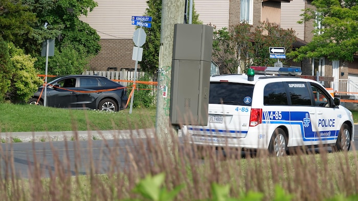 Un véhicule accidenté en arrière plan avec un véhicule du SPVM en avant.