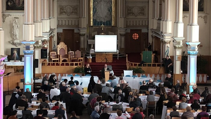 À l'intérieur de l'église, plusieurs personnes sont assises autour de tables rondes.