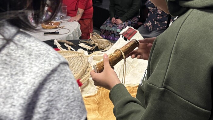 Un jeune individu manipule un objet en bois.