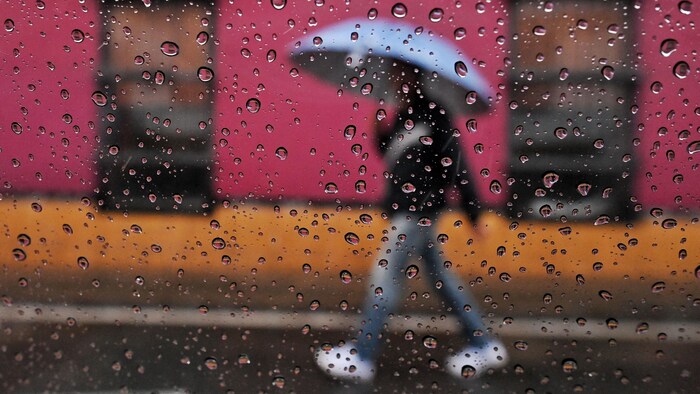 Un homme marche avec un parapluie.