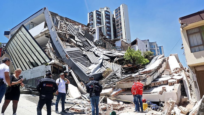 Des personnes se trouvent près d’un bâtiment effondré à la suite d’un tremblement de terre survenu à Manizales.
