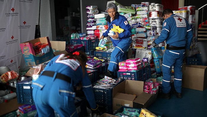 Des membres de la Croix-Rouge colombienne rassemblent des produits d'hygiène pour les victimes.