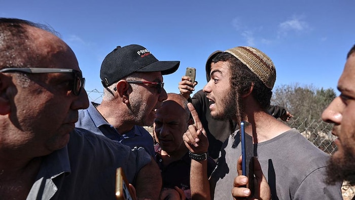 Un homme portant une casquette et un homme portant une kippa se disputent.