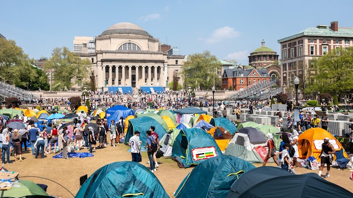 Plusieurs tentes et de nombreuses personnes sur le campus ensoleillé de Columbia.