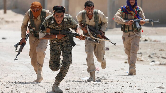 Des combattants kurdes montent à l'assaut dans la ville de Raqqa, en Syrie.