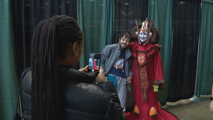 Une personne qui pose en photo avec une participante déguisée en reine Amidala, des films La Guerre des Étoiles.