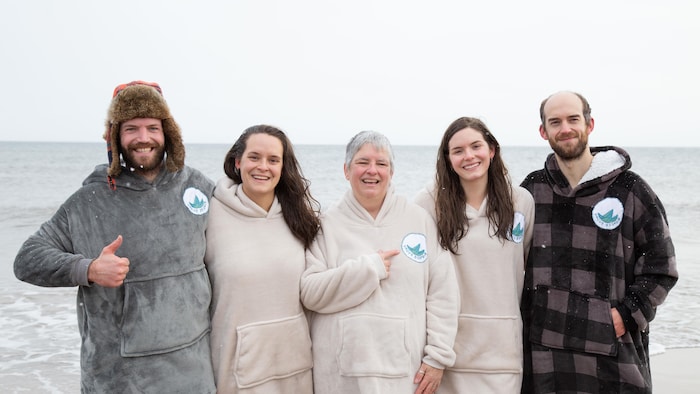 Deux hommes et trois femmes souriant à la caméra sur une plage des Îles-de-la-Madeleine un 1er janvier