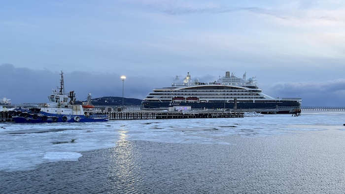 Un bateau de croisière est amarré à un quai l'hiver.