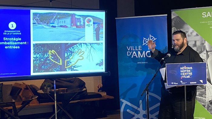 Luc Valcourt présente des diapositives derrière un lutrin.