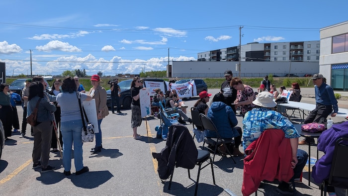 Des personnes manifestent dans un stationnement.