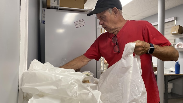 Un homme met des repas préparés dans un sac en plastique.