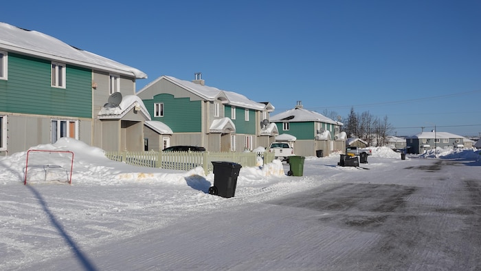 Plusieurs maisons semblables sur une rue enneigée de Matimekush-Lac John.