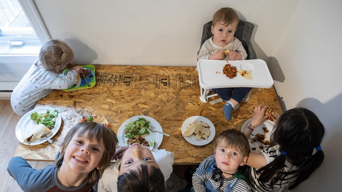 Six enfants attablés mangent leur repas.