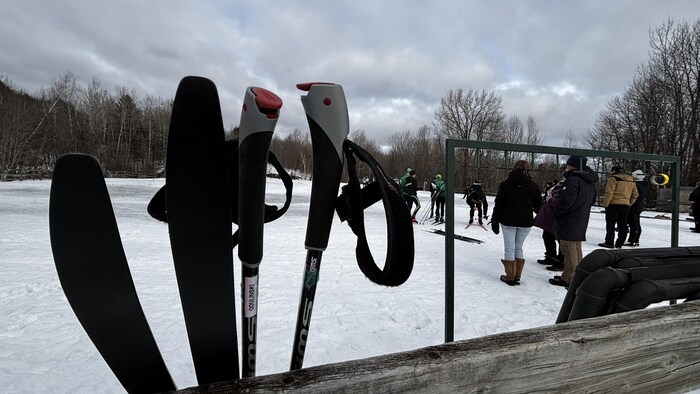 Des skis de fond et des bâtons avec des gens en arrière-plan.
