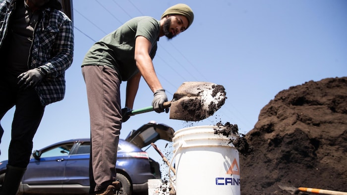 Un citoyen met du compost dans un contenant.