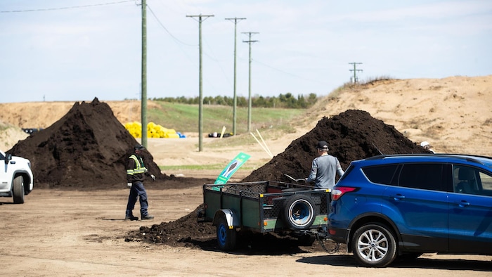 Deux tas de compost sont à la disposition des citoyens. Deux citoyens en récoltent.