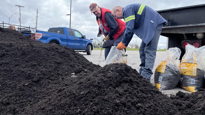 Deux personnes remplissent des sacs de compost.