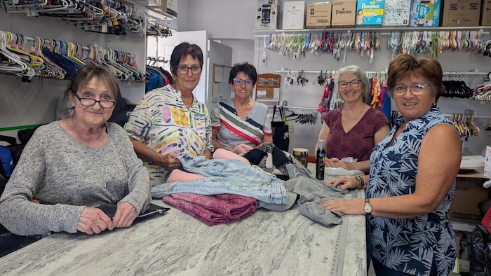 Cinq bénévoles se tiennent derrière un comptoir et sourient pour la photo.