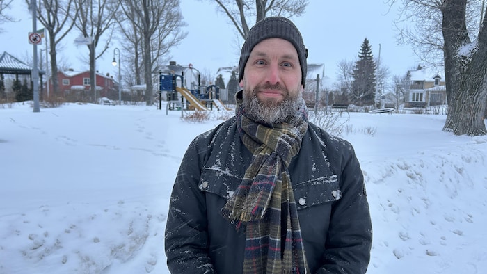 Un homme pose en hiver dans un parc.