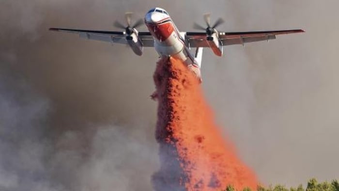 Un avion déverse de l'eau sur un feu de forêt.