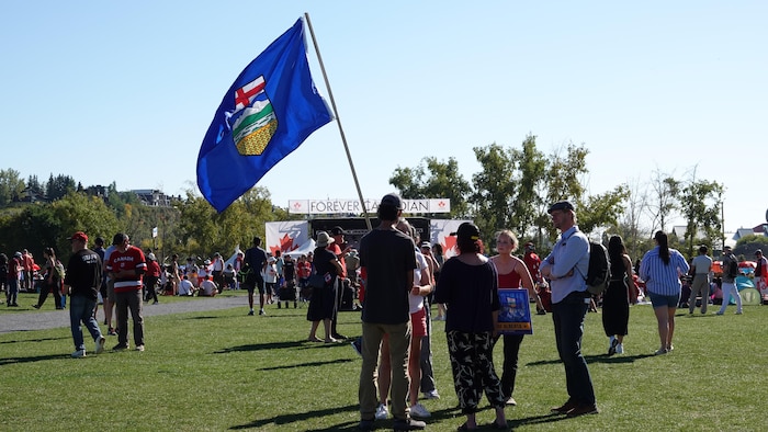 Une personne tenant un drapeau albertain discute avec quelqu'un.