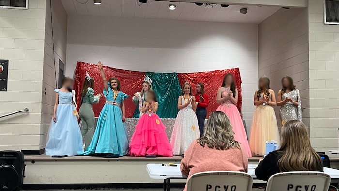 Six jeunes filles qui portent des robes sont debout sur une scène.