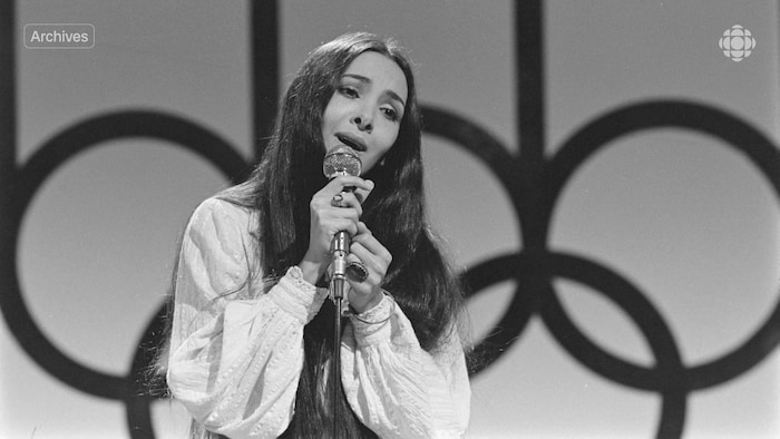 Une femme chante une chanson en tenant un micro dans ses mains.