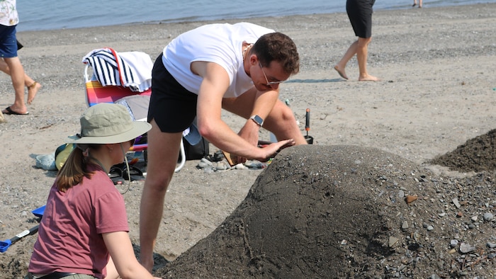 Un homme et un femme manipulent du sable sur la plage.