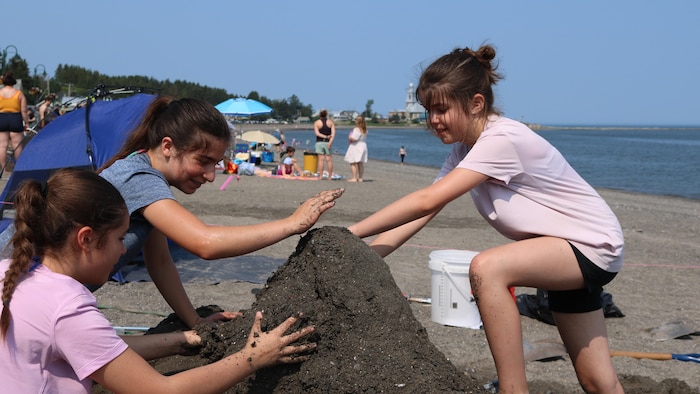Une famille érige une butte de sable. 