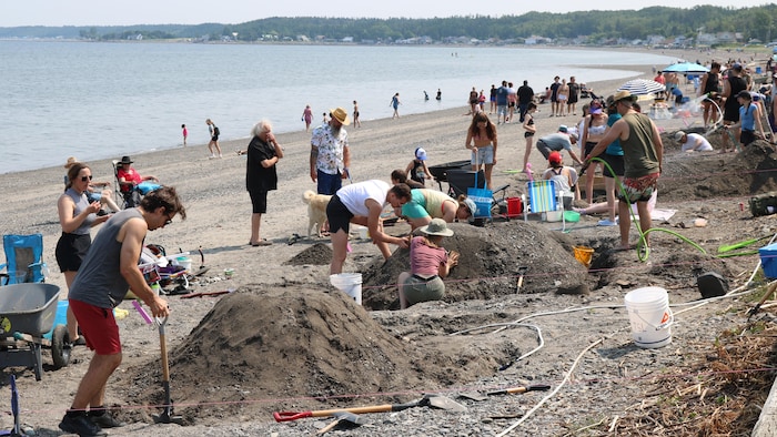 La plage de Sainte-Luce achalandée. Des équipes s'affairent à construire des châteaux de sable. 