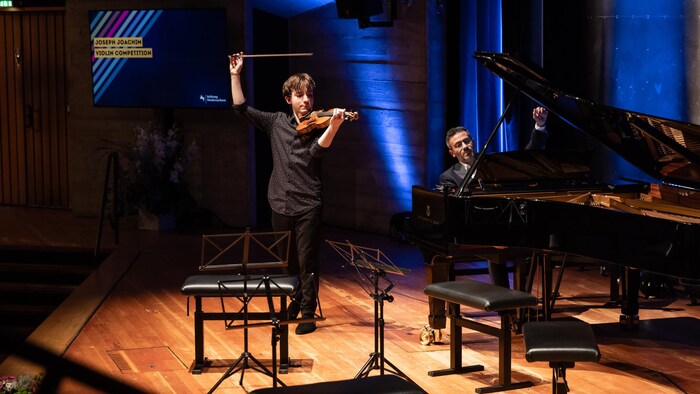 Accompagné d'un pianiste, Jacques Forestier est sur scène avec son violon.