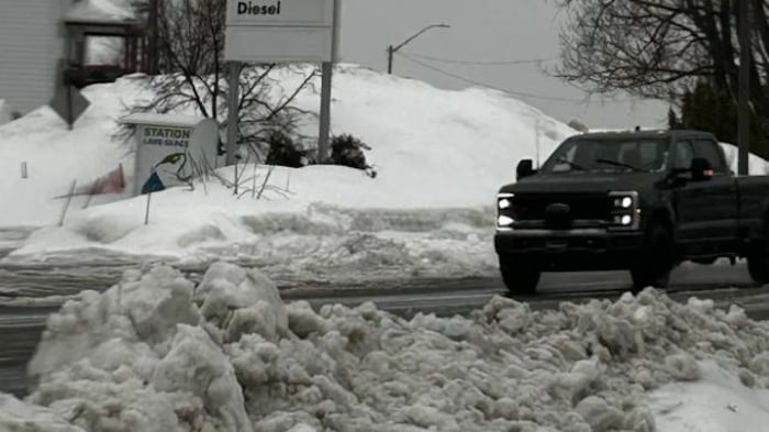 Un véhicule de type pick-up roule dans une rue de Rouyn-Noranda, un gros tas de neige à l'avant-plan.
