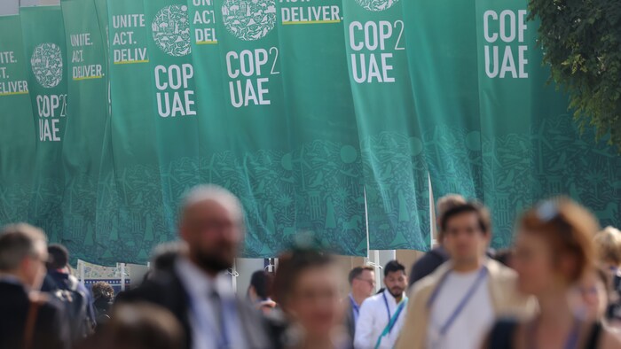 Delegados passam pelos banners da COP28. 