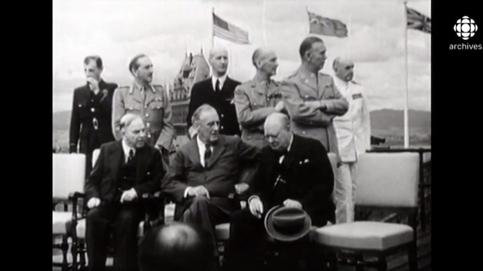 Le premier ministre canadien Mackenzie King, le premier ministre britannique Winston Churchill et le président américain Franklin D. Roosevelt sont assis devant le Château Frontenac avec des généraux debout derrière eux.