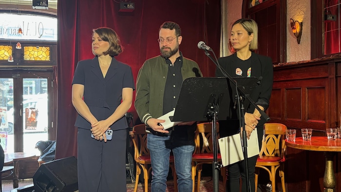 Deux femmes et un homme écoutent une question du public sur la scène.