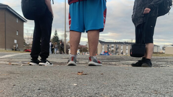 Des élèves avec leurs sacs à dos près de leur école.