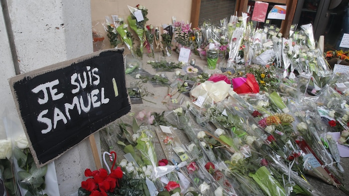 Une pancarte où l'on peut lire « Je suis Samuel », entourée de fleurs.
