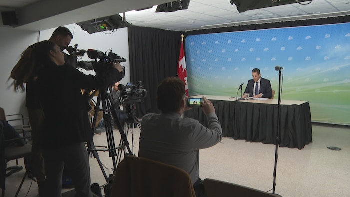 Rob Lantz donne une conférence de presse devant les journalistes.