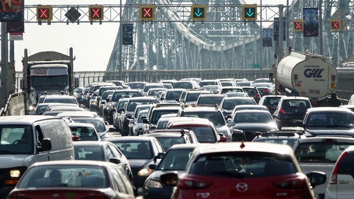 Plusieurs véhicules sont pris dans la congestion routière du pont Jacques-Cartier à l'heure de pointe matinale à Montréal, alors qu'on voit les feux de circulation signalant les voies ouvertes et fermées dans les deux sens.