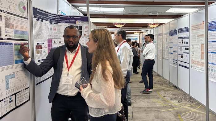 Des participants discutent devant des affiches de recherche lors d'un congrès scientifique.