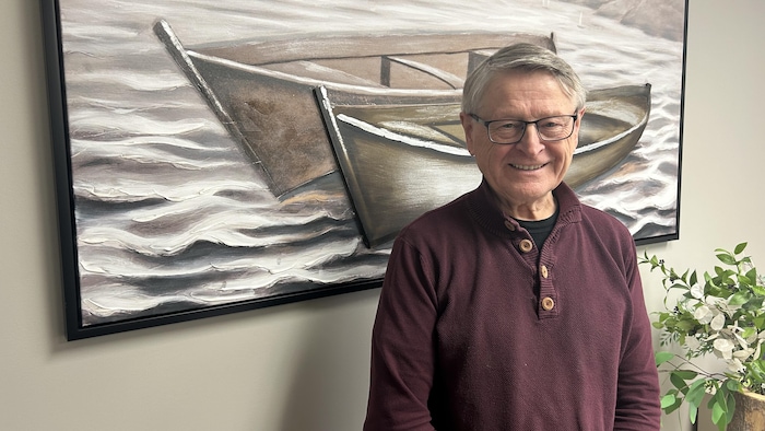 Un homme se tient devant un tableau.